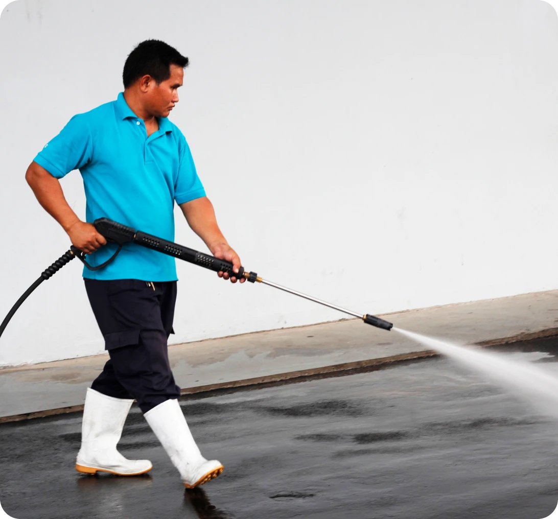 Man pressure washing pavement